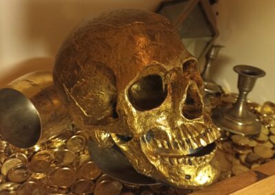 Vergoldeter Totenschädel und Goldmünzen im Live Escape Game Unter Deck